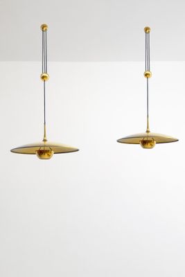 two brass lamps hanging from the ceiling in a white room