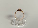 a gold ring with a flower on it on a clear stand
