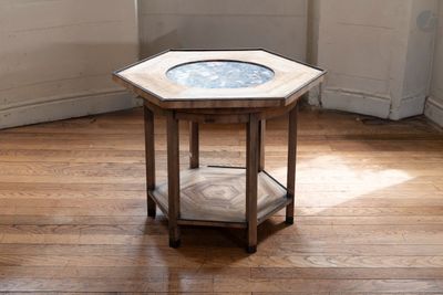 une petite table en bois avec un plateau en verre, posée sur un parquet en bois massif