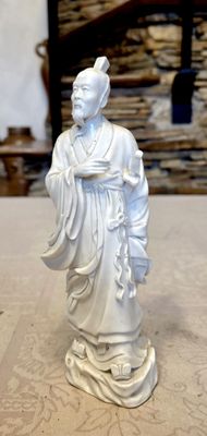 a white statue of a man holding a bowl on a table