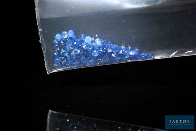 un sachet de cristaux bleus posé sur une surface noire