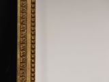 a close up of a gold framed mirror on a black wall