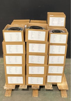 Plusieurs cartons sont empilés sur une palette devant un mur noir