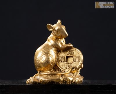 une figurine en or représentant une souris tenant une pièce d'or