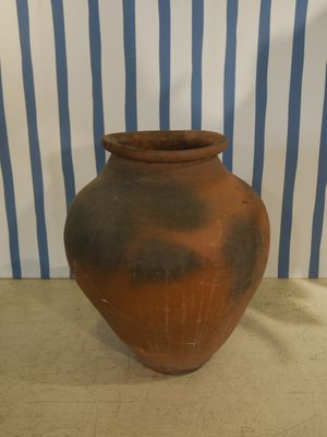 a brown vase sitting on a table in front of a blue and white striped wall