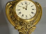 une horloge dorée avec des chiffres romains accrochée au mur