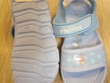 a pair of children ' s sandals on a wooden floor