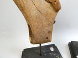 une sculpture en bois représentant une tête de femme, posée sur un socle