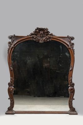 un miroir au cadre en bois richement sculpté, posé sur une surface blanche