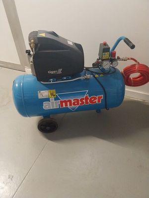 a blue air compressor sitting on the floor next to a wall