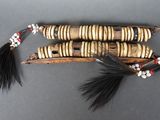 trois morceaux de bois ornés de perles noires et blanches et d'une plume