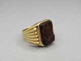 a close up of a gold ring with a red stone in it