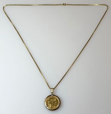 a gold necklace with a coin on a chain