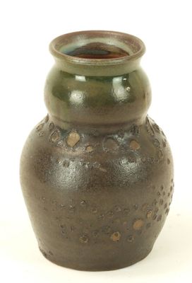 a brown vase with holes in it on a white surface