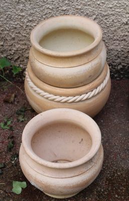 three clay pots sitting next to each other on the ground