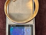 une balance numérique sur laquelle est posé un bracelet en or