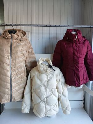 deux vestes et un manteau sont posés sur un banc devant un mur
