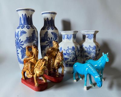 Plusieurs vases et figurines sont posés sur une surface blanche