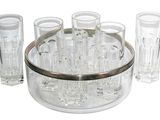des bouteilles et des verres sont disposés en cercle sur une surface blanche