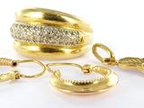 deux bagues en or et une paire de boucles d'oreilles posées sur une surface blanche