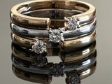 two gold and silver rings with diamonds on a reflective surface