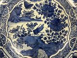 a blue and white plate with birds and flowers on it