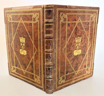 an old book with a golden cover sitting on top of a white table