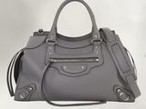 le grand sac gris est posé sur une surface blanche