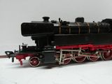 un train miniature noir et rouge posé sur une surface blanche