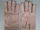 pair of beige leather gloves with stitching on them on a gray surface