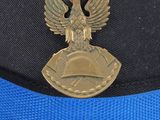 a black hat with a blue band and a gold eagle on it