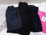three pairs of black, white, and pink sweatpants on a bed