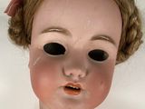 a close up of a doll with a red bow on it ' s head