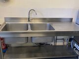 a stainless steel sink in a kitchen with a microwave