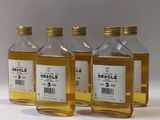 trois petites bouteilles d'huile posées sur une surface blanche