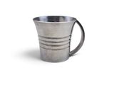 une tasse en argent posée sur une surface blanche