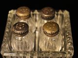 bottles of salt and pepper shakers in a glass container on a black surface