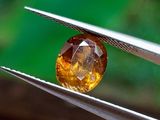 un gros plan d'un diamant jaune tenu par une paire de pinces