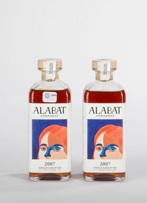 deux bouteilles d'alcool sont posées l'une à côté de l'autre sur une surface blanche