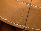 a person holding a brown leather wallet with white stitching on it
