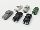 several toy cars are lined up in a row on a white surface