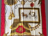 a red and gold scarf with a picture of a horse drawn carriage