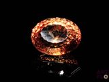 a close up of an orange diamond on a black surface