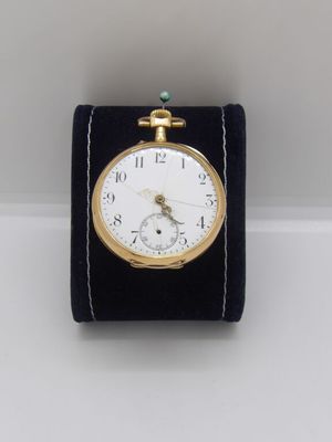 a small gold pocket watch on a black velvet stand