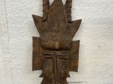 an old wooden mask sitting on top of a piece of wood