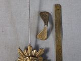 a metal object with a gold sunburst on it next to a pair of scissors and a piece of metal