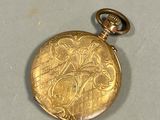 a gold pocket watch that is on display on a table
