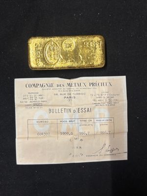 a gold bar sitting on top of a piece of paper next to a piece of paper