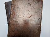 un vieux livre à la couverture marron posé sur une table blanche