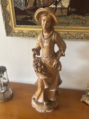 a statue of a woman holding a basket of flowers on a table